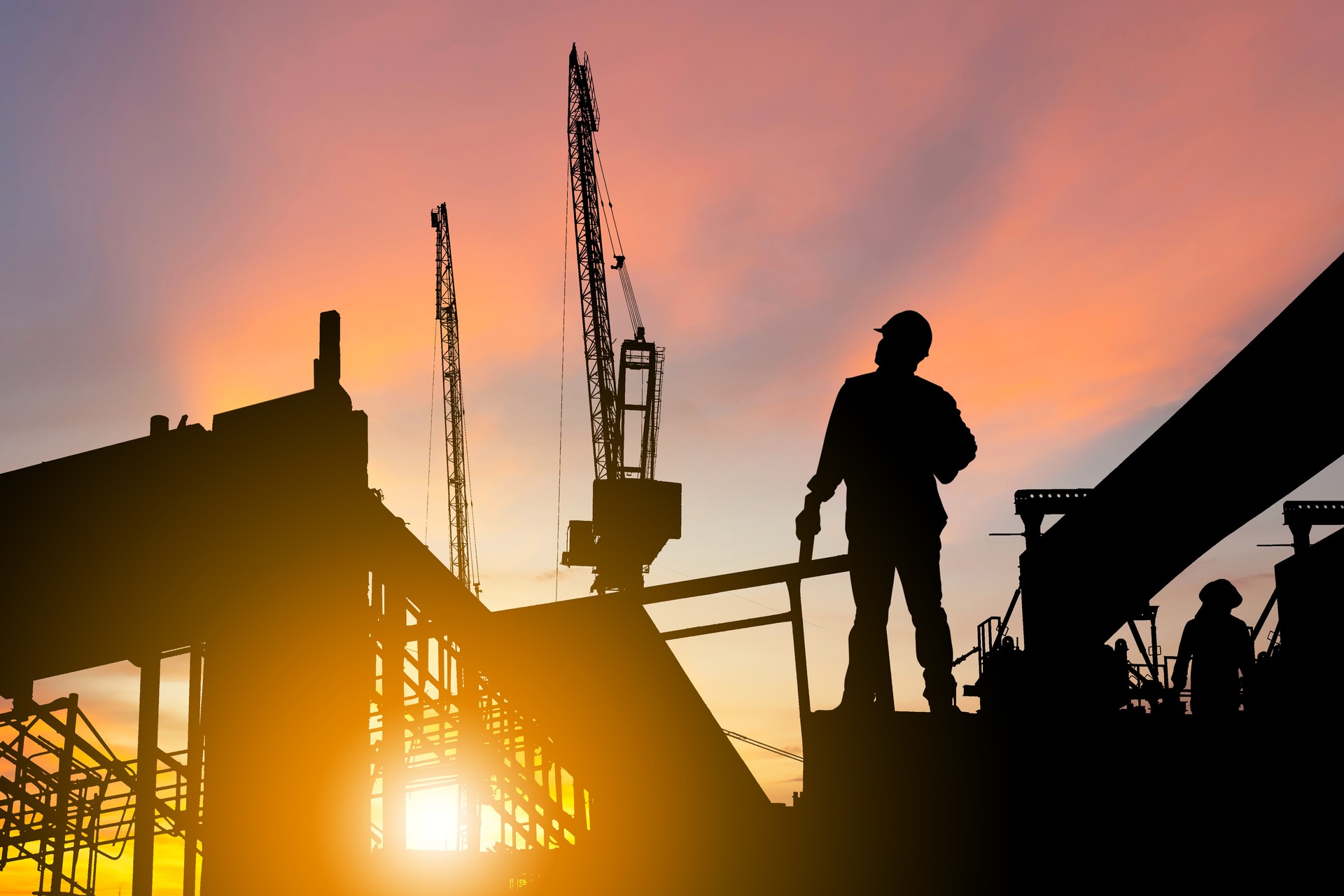 Silhouette of Engineer and worker on building site, construction site at sunset in evening time